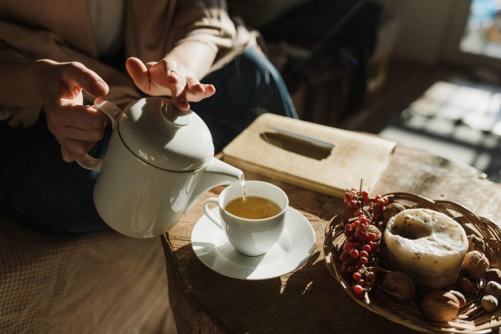Derramando chá quente lentamente em uma xícara de cerâmica rústica - slow living