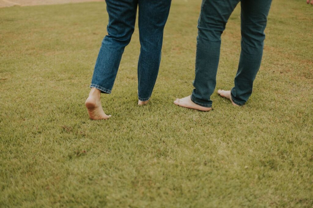 Pés descalços caminhando calmamente sobre a grama verde - slow living