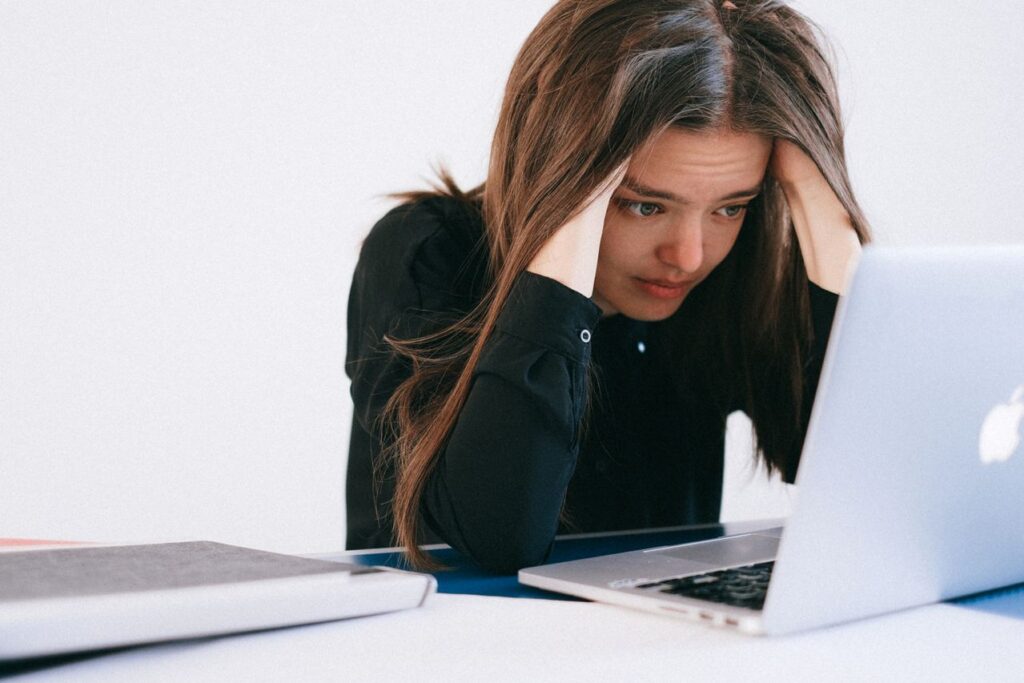 Mulher sobrecarregada olhando para a tela do notebook - paradoxo da produtividade