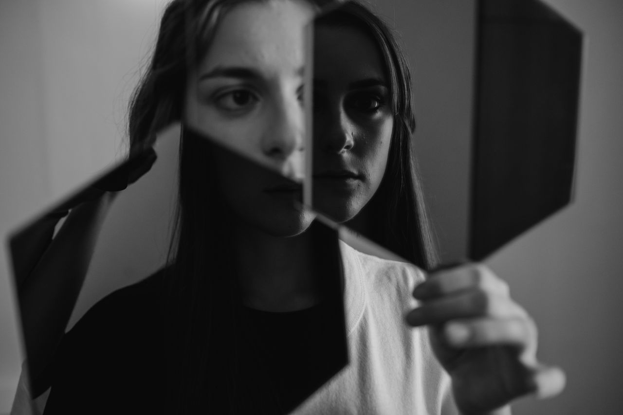 ditadura da positividade - Pessoa forçando um sorriso no espelho, com reflexo triste ou cansado