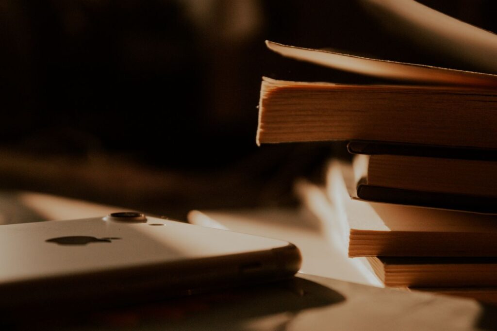economia da distracao - Pilha de livros em uma mesa ao lado de um smartphone com a tela acesa