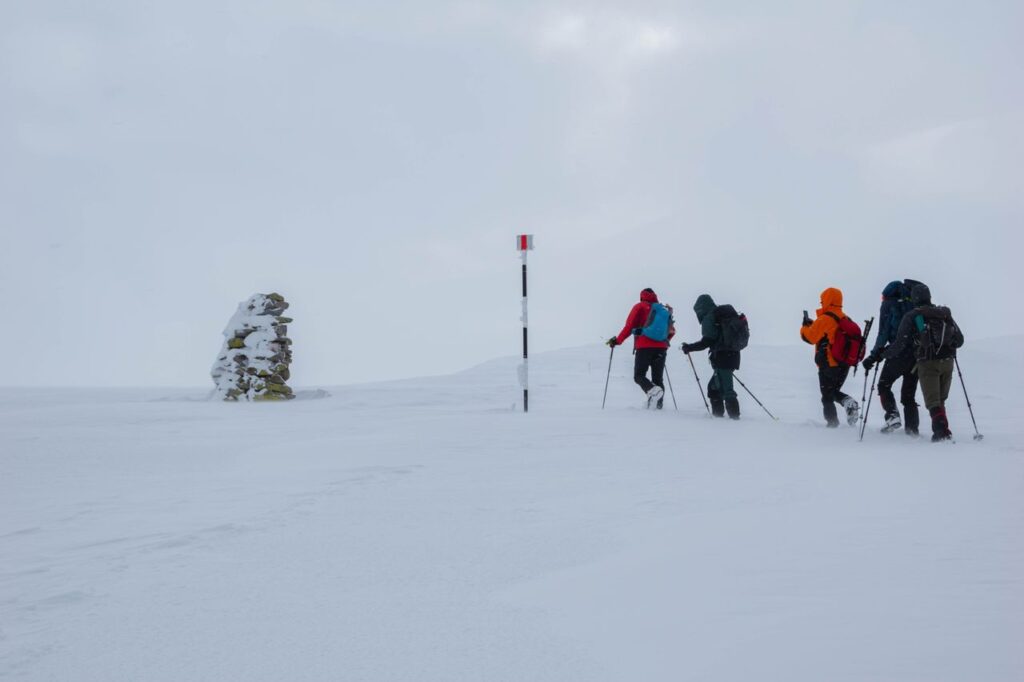 a arte de falhar e recomeçar - Um explorador ou pequena equipe caminhando sob neve intensa, vestindo roupas de frio pesadas, enfrentando o vento e o terreno congelado