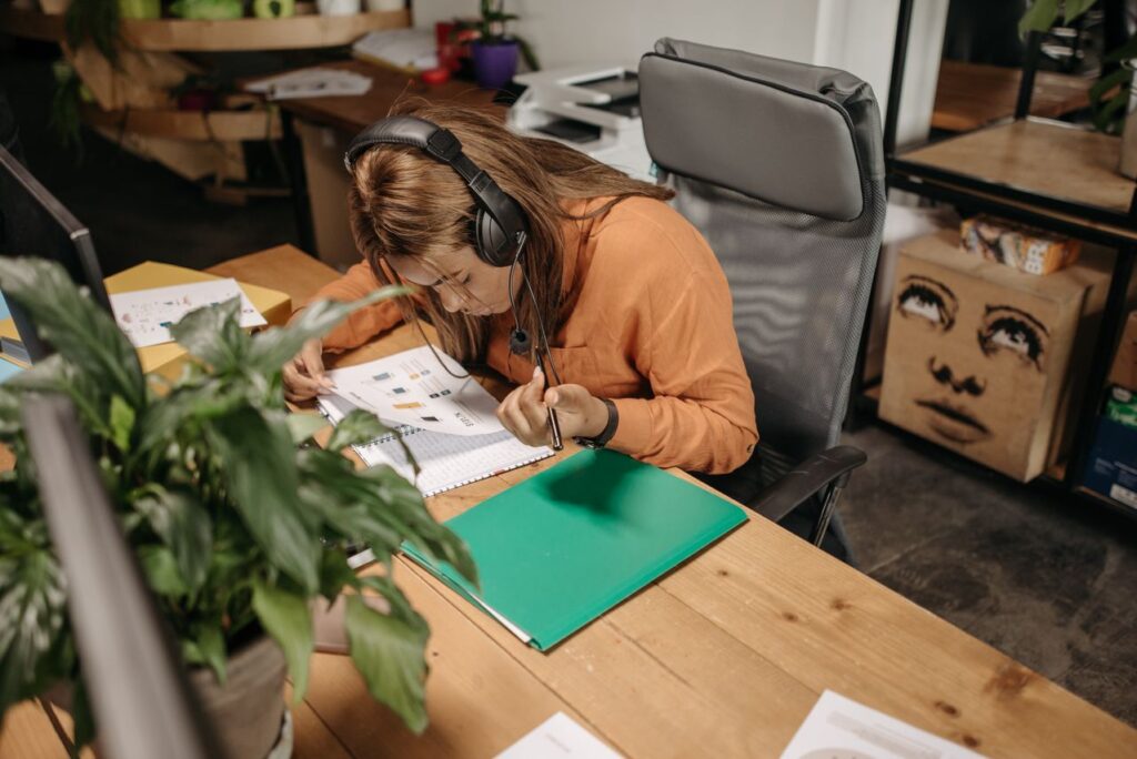 economia da atenção - Uma pessoa imersa em uma única tarefa seja escrevendo em um caderno, lendo ou trabalhando no computador usando fones de ouvido, em um ambiente limpo, bem iluminado e sem elementos visuais poluídos