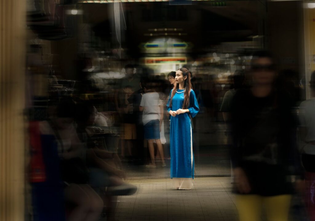 A última das liberdades humanas -Uma pessoa caminhando com calma por uma rua movimentada com fundo ligeiramente desfocado (efeito bokeh ou longa exposição), simbolizando quem mantém o controle interior no meio da multidão/caos