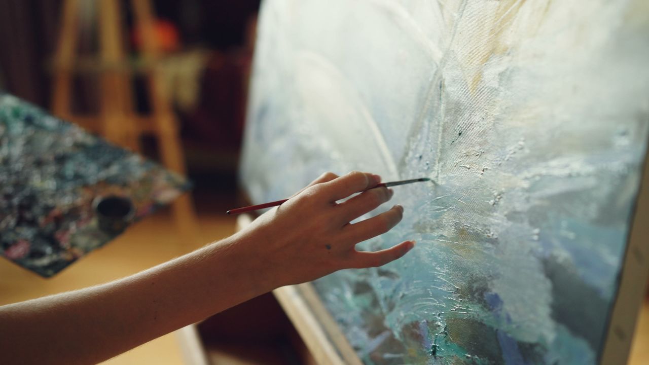 frida kahlo - Foco nas mãos do artista em ação, pincéis e texturas de tinta a óleo na tela