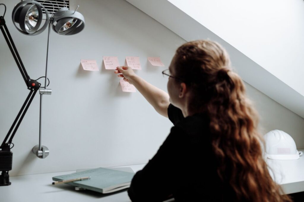 autismo em adultos - Mãos de um adulto organizando um planner, bloco de anotações ou mural de post-its com passos visuais claros