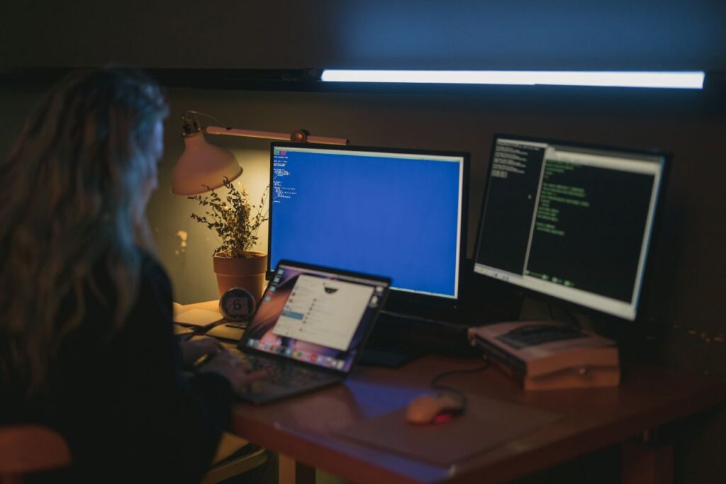 espetaculo corporativo - pessoa sobre a mesa do escritório em uma sala escura, iluminado apenas pela tela do computador cercada por papéis ou gráficos de metas