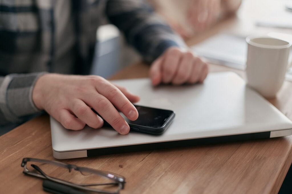 exautão no linkedin - Mãos fechando a tampa de um notebook ou virando o celular de cabeça para baixo sobre a mesa de trabalho