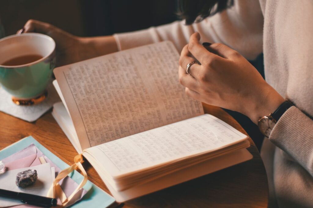 padrões mentais - pessoa compenetrada escrevendo em um caderno/diário em uma mesa organizada, iluminada por luz natural