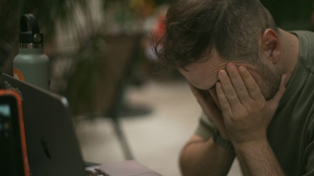 exautão no linkedin - profissional em frente ao laptop ou segurando o smartphone com a cabeça apoiada nas mãos ou expressão de exaustão