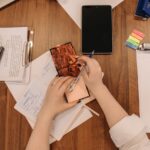 citações motivacionais - Mãos segurando uma caneta e escrevendo em um bloco de notas estético ou livro aberto em uma mesa organizada