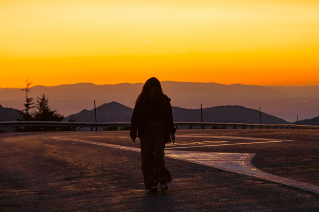 citações motivacionais - pessoa no topo de um morro/montanha ou caminhando em uma estrada ao pôr do sol com postura firme