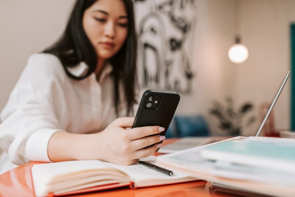 exaustão no linkedin - pessoa segurando o celular enquanto trabalha, observando métricas ou notificações no smartphone
